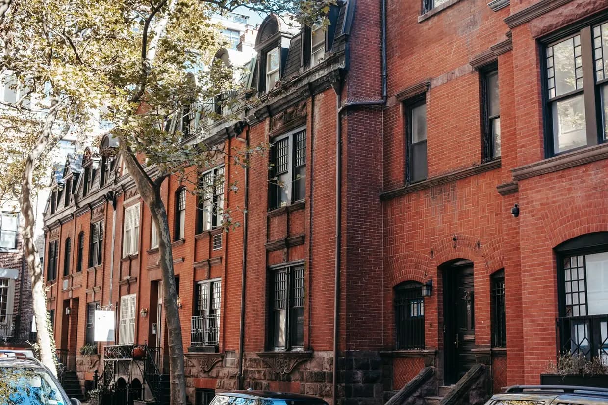 A row of red brick houses with front steps along a city street